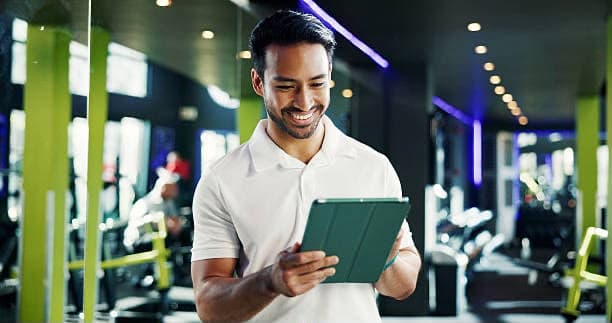 A coach checking the schedule on a tablet on the gym floor