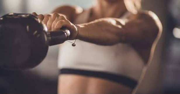A member holding a kettlebell mid-workout